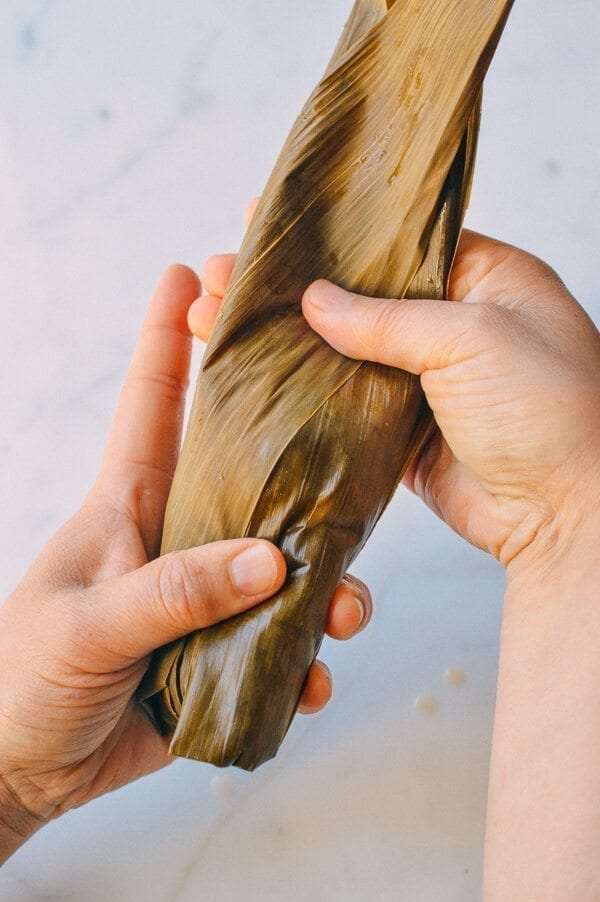 Before you start, there are a few things to remember: You must cut away at least half an inch off the bottom of every leaf you use. Make sure the kitchen twine won’t break easily. To do this, it’s best to wet the twine first by soaking it in a bowl of water. It’s best to tie one end of the twine to an anchor point or kitchen fixture (e.g. you kitchen sink), because you will only have one hand to tie the zongzi. Your other hand will be holding the zongzi. Or have someone help you out! Making zongzi is like making a big batch of dumplings or wontons—all hands on deck! Just make sure that the newbies are holding the strings and the seasoned pros are doing the folding! Hah! If leaves rip anywhere during the wrapping process, you’ll need to start over and discard the ripped leaf. That’s why I call for more leaves than is technically needed. Some of the leaves are bound to get ripped.
