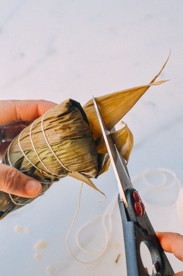 Before you start, there are a few things to remember: You must cut away at least half an inch off the bottom of every leaf you use. Make sure the kitchen twine won’t break easily. To do this, it’s best to wet the twine first by soaking it in a bowl of water. It’s best to tie one end of the twine to an anchor point or kitchen fixture (e.g. you kitchen sink), because you will only have one hand to tie the zongzi. Your other hand will be holding the zongzi. Or have someone help you out! Making zongzi is like making a big batch of dumplings or wontons—all hands on deck! Just make sure that the newbies are holding the strings and the seasoned pros are doing the folding! Hah! If leaves rip anywhere during the wrapping process, you’ll need to start over and discard the ripped leaf. That’s why I call for more leaves than is technically needed. Some of the leaves are bound to get ripped.