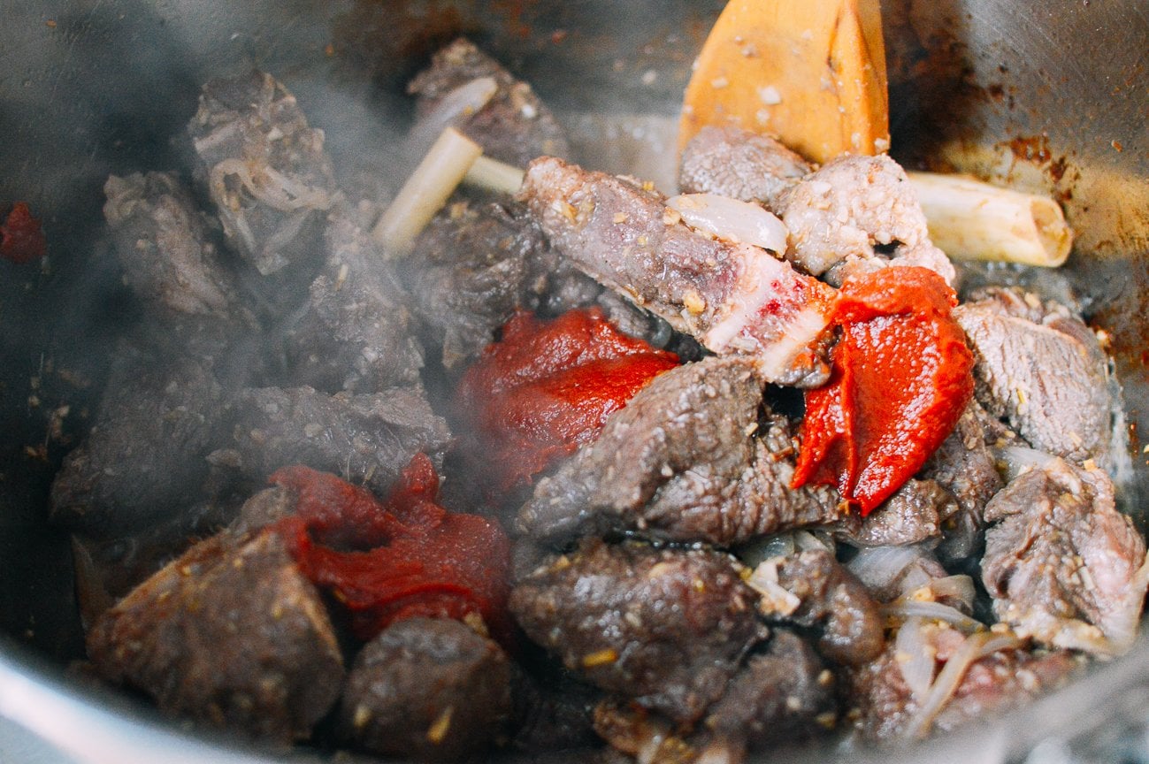 adding tomato paste to beef