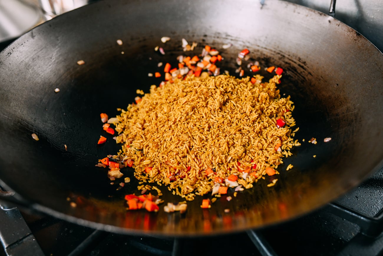 Adding prepared rice to vegetables in wok