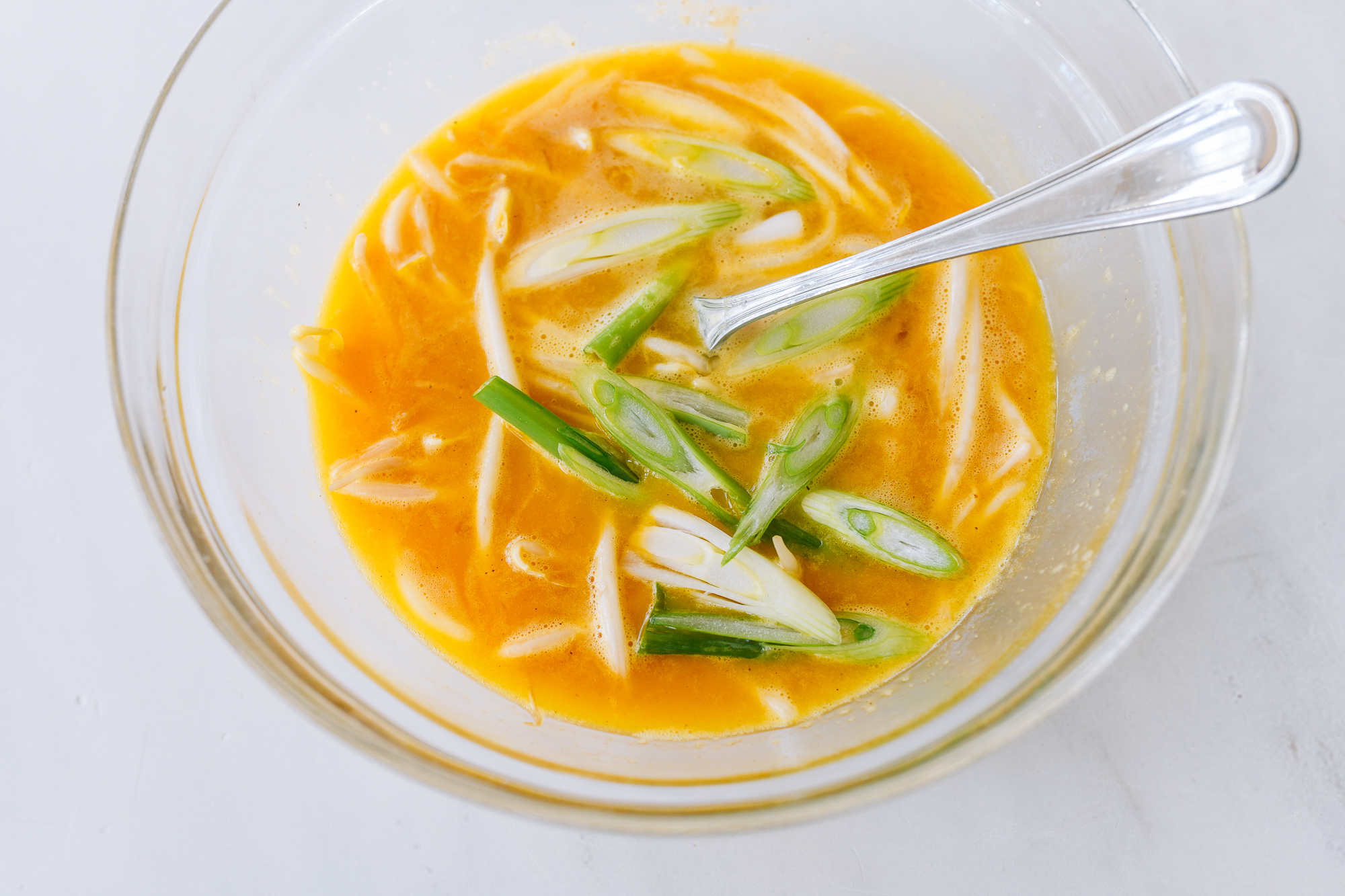 scallion whites added to beaten eggs with bean sprouts