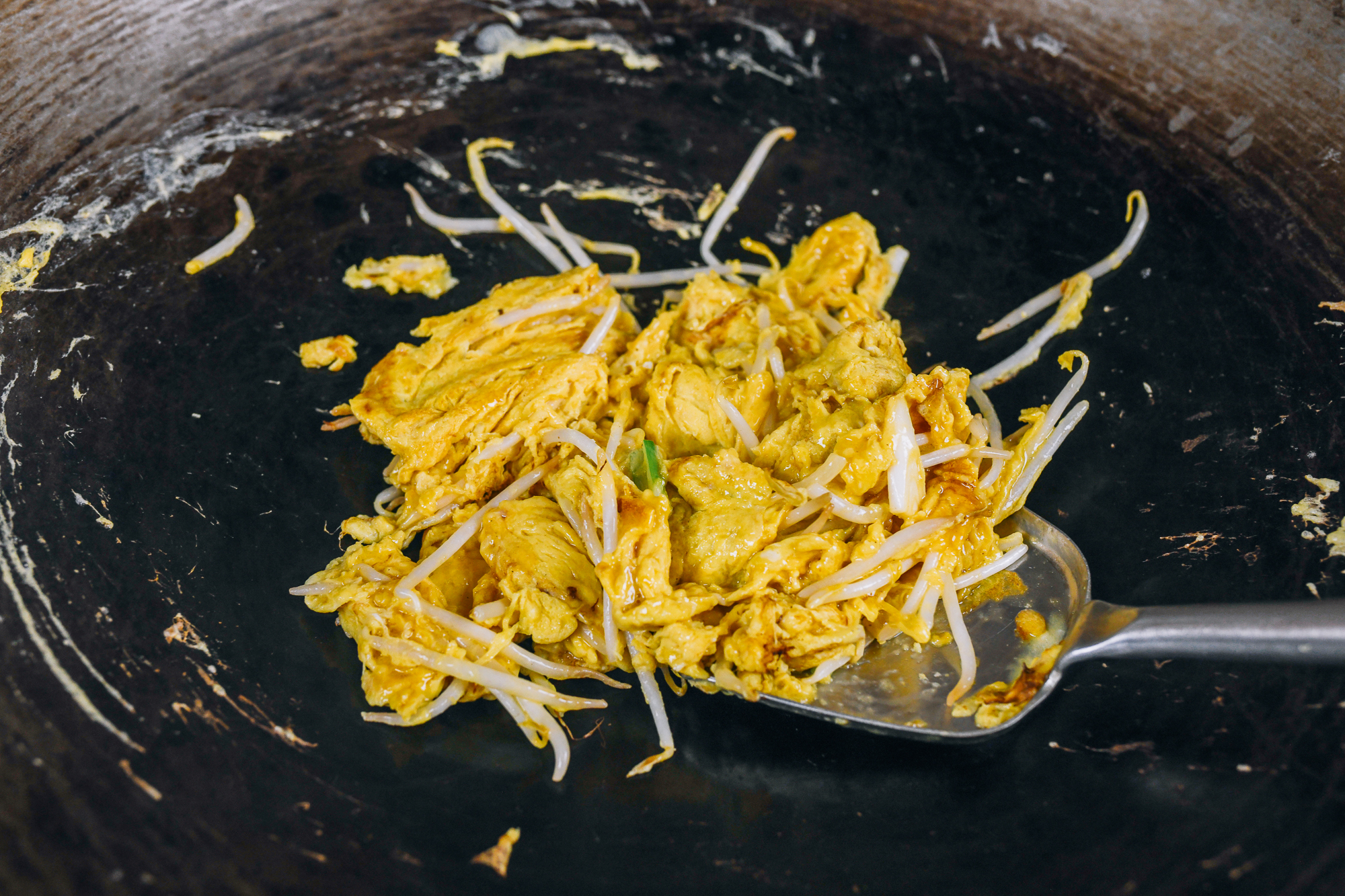 scrambled eggs in wok with bean sprouts and scallions