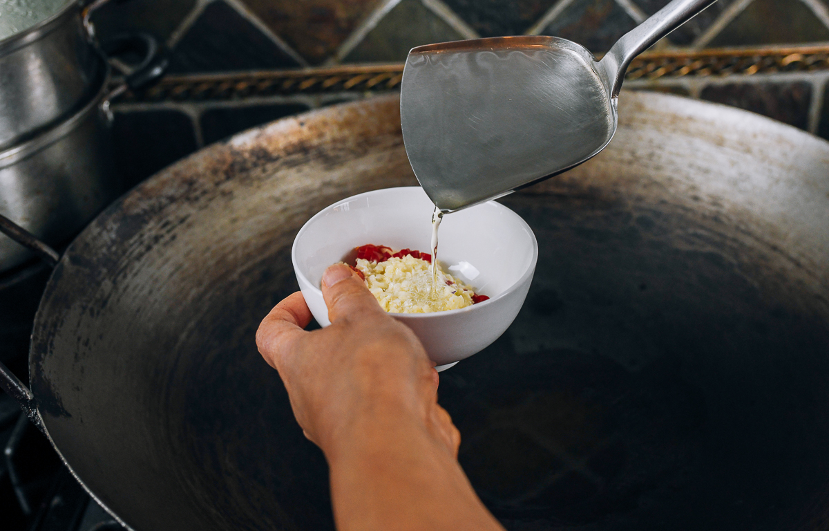 pouring hot oil over chilies and garlic