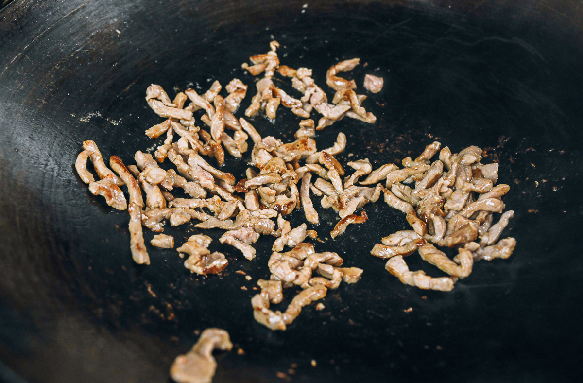 seared pork strips in wok